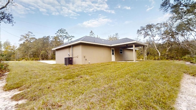 back of house with central AC unit and a yard