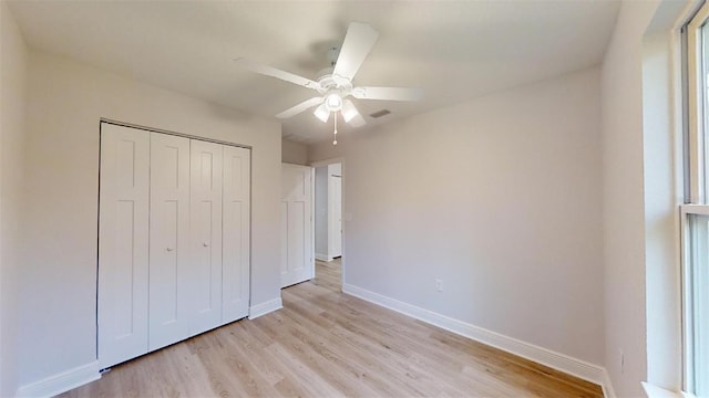 unfurnished bedroom with ceiling fan, light wood-type flooring, and a closet