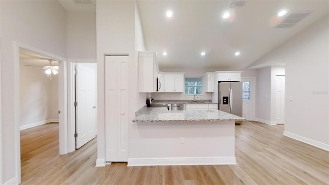 kitchen with light stone counters, light hardwood / wood-style flooring, white cabinets, and stainless steel appliances