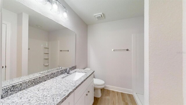 bathroom with a shower, vanity, hardwood / wood-style flooring, and toilet