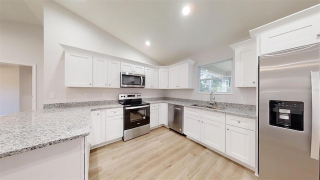 kitchen featuring appliances with stainless steel finishes, light wood-type flooring, vaulted ceiling, sink, and white cabinets