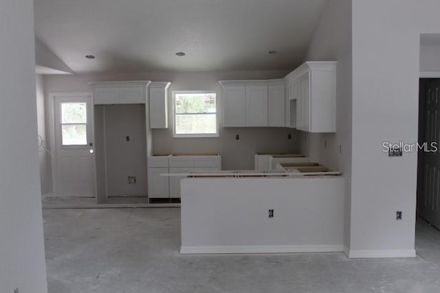 kitchen featuring a healthy amount of sunlight, white cabinetry, and vaulted ceiling