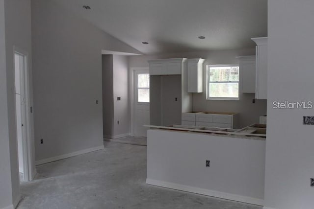 kitchen with a wealth of natural light, white cabinets, and lofted ceiling