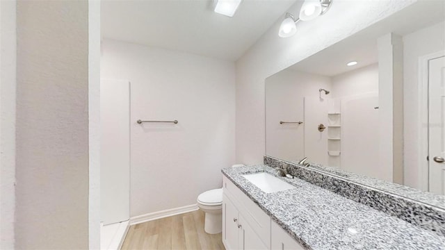 bathroom with hardwood / wood-style flooring, toilet, vanity, and walk in shower