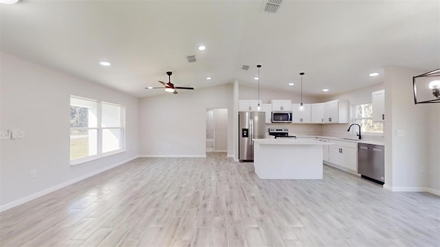 kitchen with a center island, appliances with stainless steel finishes, white cabinets, sink, and pendant lighting