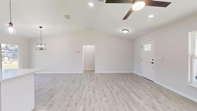 unfurnished living room with light hardwood / wood-style floors, a wealth of natural light, and ceiling fan with notable chandelier