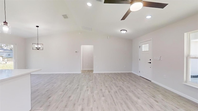 unfurnished living room featuring plenty of natural light, ceiling fan with notable chandelier, and light hardwood / wood-style floors