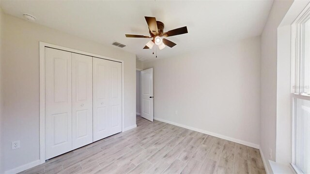 unfurnished bedroom with light wood-type flooring, a closet, and ceiling fan