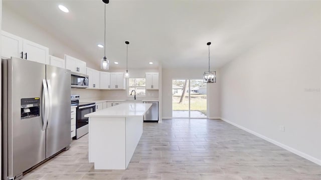 kitchen featuring a center island, white cabinetry, stainless steel appliances, sink, and hanging light fixtures