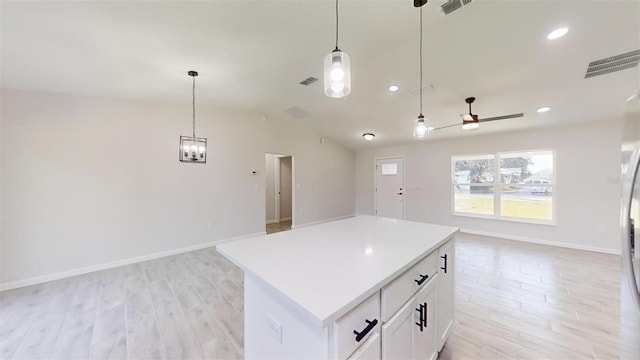 kitchen featuring decorative light fixtures, white cabinetry, light hardwood / wood-style flooring, and a kitchen island