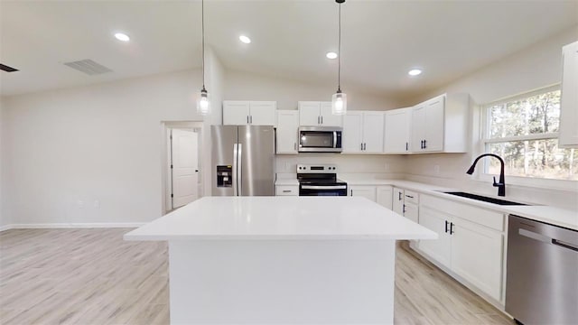 kitchen with white cabinets, a kitchen island, appliances with stainless steel finishes, and sink