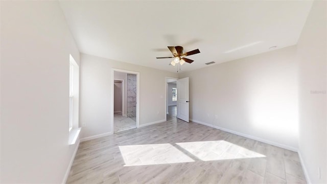 unfurnished bedroom featuring a spacious closet, a closet, ceiling fan, and light wood-type flooring