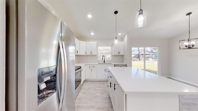 kitchen with white cabinets, decorative light fixtures, a center island, and appliances with stainless steel finishes