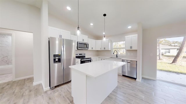 kitchen featuring white cabinets, a center island, decorative light fixtures, stainless steel appliances, and sink