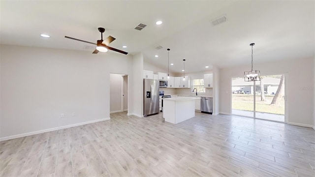 kitchen featuring decorative light fixtures, sink, white cabinets, a center island, and stainless steel appliances