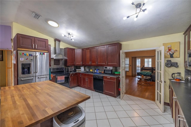 kitchen featuring french doors, wall chimney range hood, vaulted ceiling, decorative backsplash, and black appliances