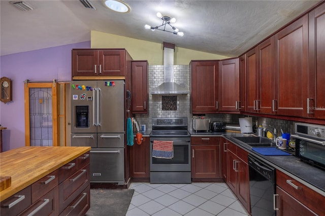 kitchen featuring wall chimney exhaust hood, backsplash, vaulted ceiling, light tile patterned floors, and appliances with stainless steel finishes