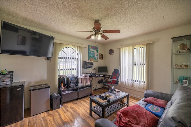 living room featuring a textured ceiling, light hardwood / wood-style floors, and ceiling fan