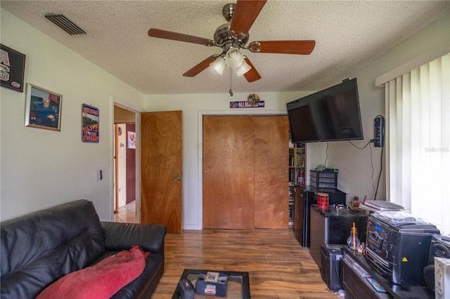 living room with a textured ceiling, dark hardwood / wood-style flooring, a wealth of natural light, and ceiling fan