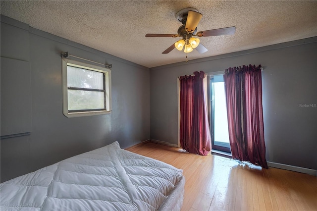 bedroom with ceiling fan, light hardwood / wood-style floors, and a textured ceiling