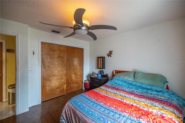 bedroom featuring ceiling fan, dark wood-type flooring, a textured ceiling, and a closet