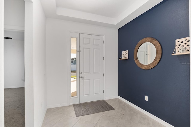 foyer entrance with light tile patterned floors and a tray ceiling