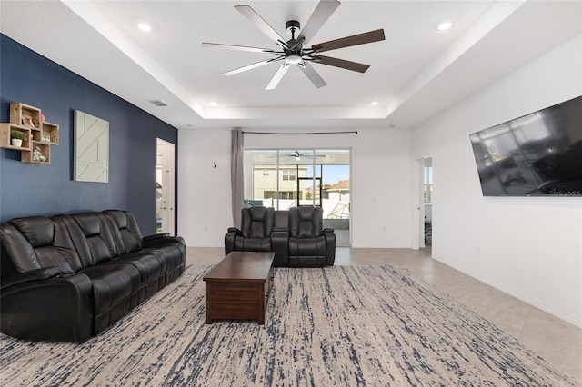 living room with ceiling fan, light tile patterned floors, and a raised ceiling