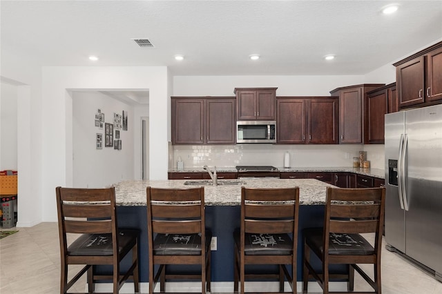 kitchen with a kitchen bar, sink, appliances with stainless steel finishes, and a kitchen island with sink