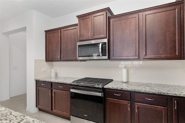 kitchen featuring light tile patterned floors, stainless steel appliances, decorative backsplash, and light stone counters