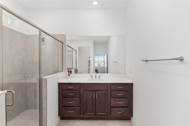 bathroom featuring a shower with shower door, vanity, and tile patterned flooring