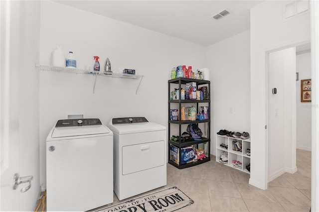 clothes washing area featuring light tile patterned floors and washer and clothes dryer