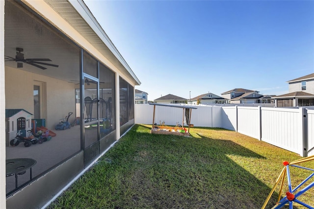 view of yard featuring a sunroom and ceiling fan