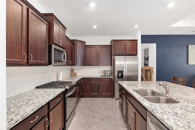 kitchen with light stone countertops, a breakfast bar, appliances with stainless steel finishes, and sink