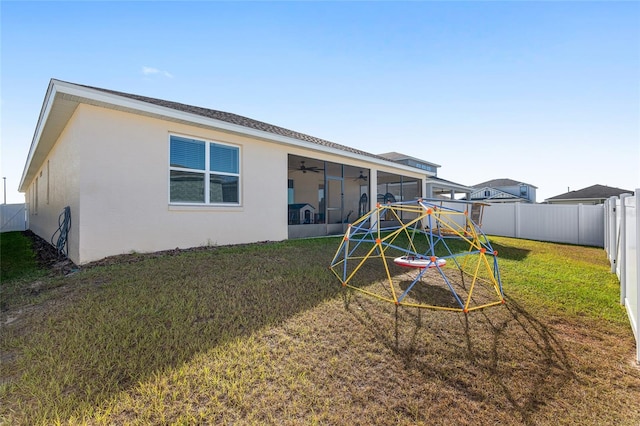 back of house with a playground, a sunroom, a yard, and ceiling fan