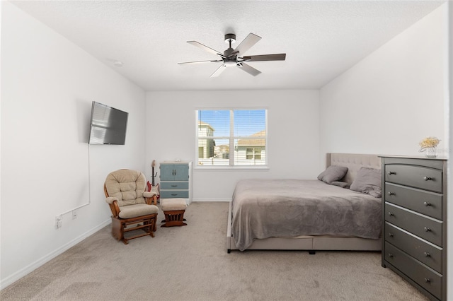 bedroom featuring a textured ceiling, light colored carpet, and ceiling fan