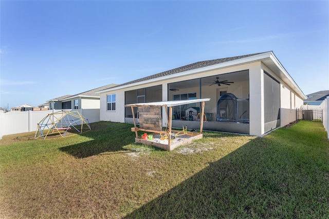 rear view of property featuring ceiling fan and a lawn