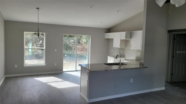 kitchen featuring white cabinetry, kitchen peninsula, stone countertops, hanging light fixtures, and sink