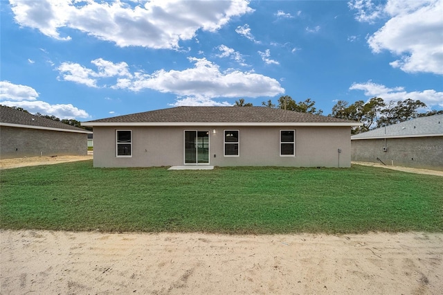 rear view of house with a lawn and stucco siding