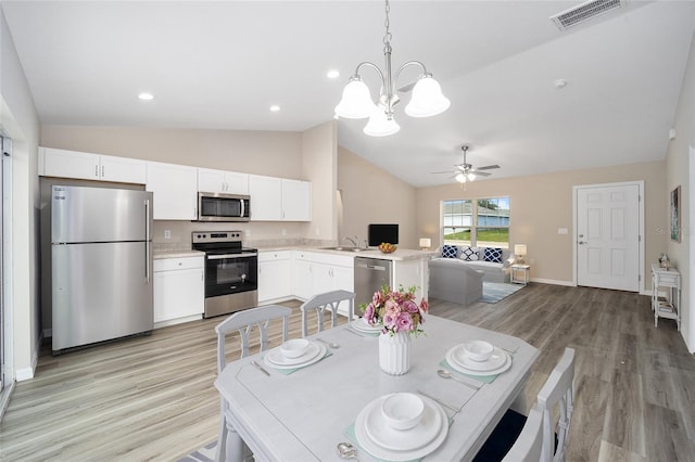 dining space with lofted ceiling, light wood-type flooring, visible vents, and baseboards