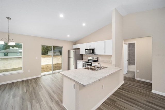 kitchen with white cabinets, a peninsula, stainless steel appliances, light countertops, and pendant lighting