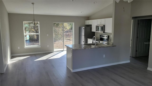 kitchen with a peninsula, light stone countertops, stainless steel appliances, white cabinetry, and pendant lighting