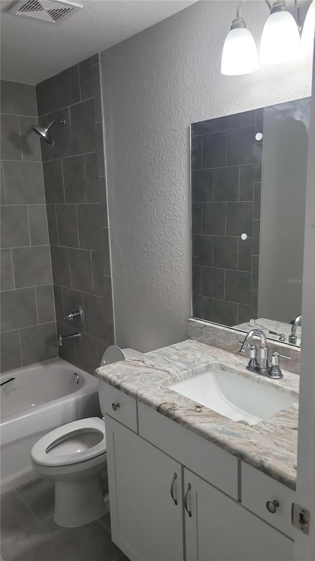 full bath featuring a textured wall, bathtub / shower combination, toilet, vanity, and visible vents