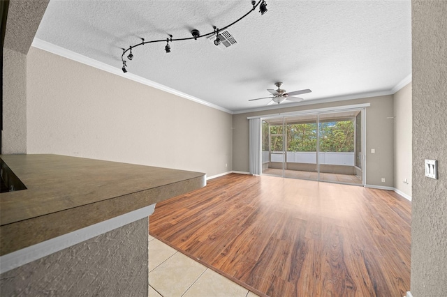 unfurnished living room with ceiling fan, crown molding, light wood-type flooring, and a textured ceiling