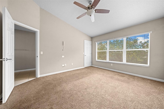 spare room featuring carpet flooring, ceiling fan, lofted ceiling, and a textured ceiling