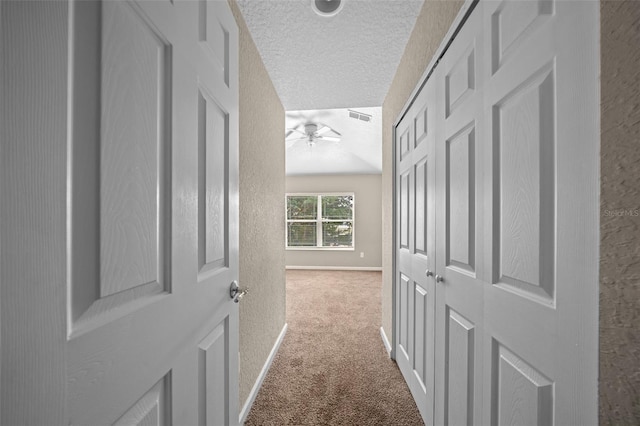 hallway with carpet flooring and a textured ceiling