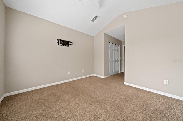 carpeted empty room featuring vaulted ceiling