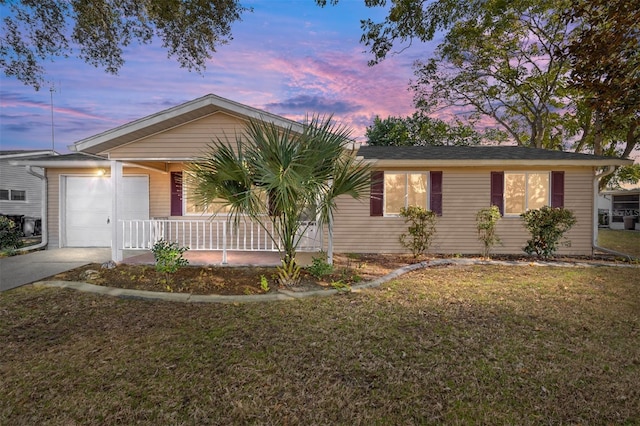 ranch-style house with a porch, a garage, and a yard