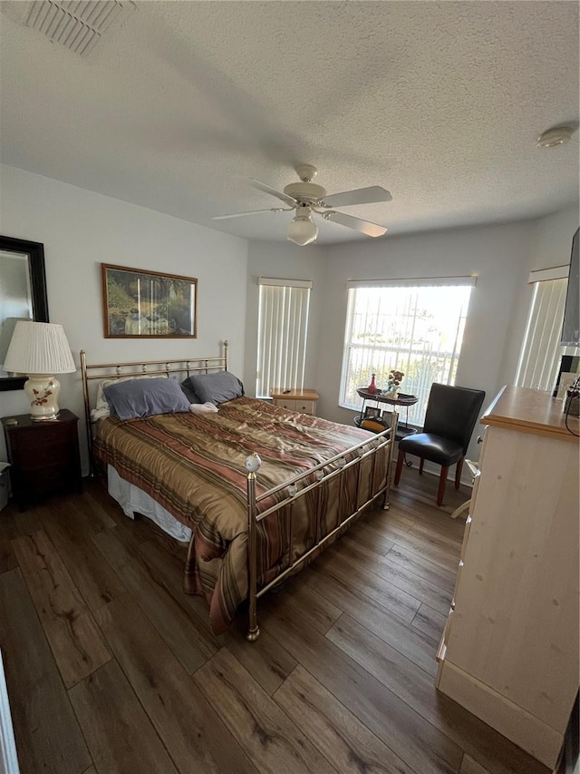 bedroom with hardwood / wood-style floors, ceiling fan, and a textured ceiling