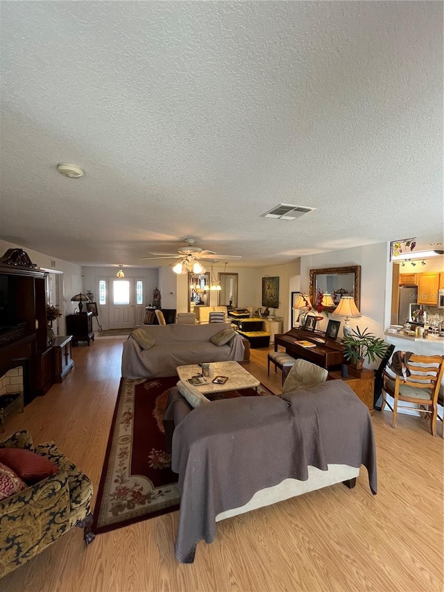 living room featuring hardwood / wood-style flooring, ceiling fan, and a textured ceiling