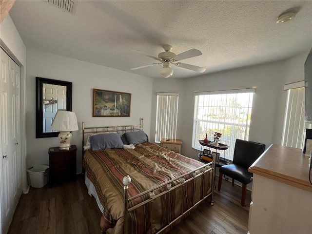 bedroom with ceiling fan, a closet, dark wood-type flooring, and a textured ceiling